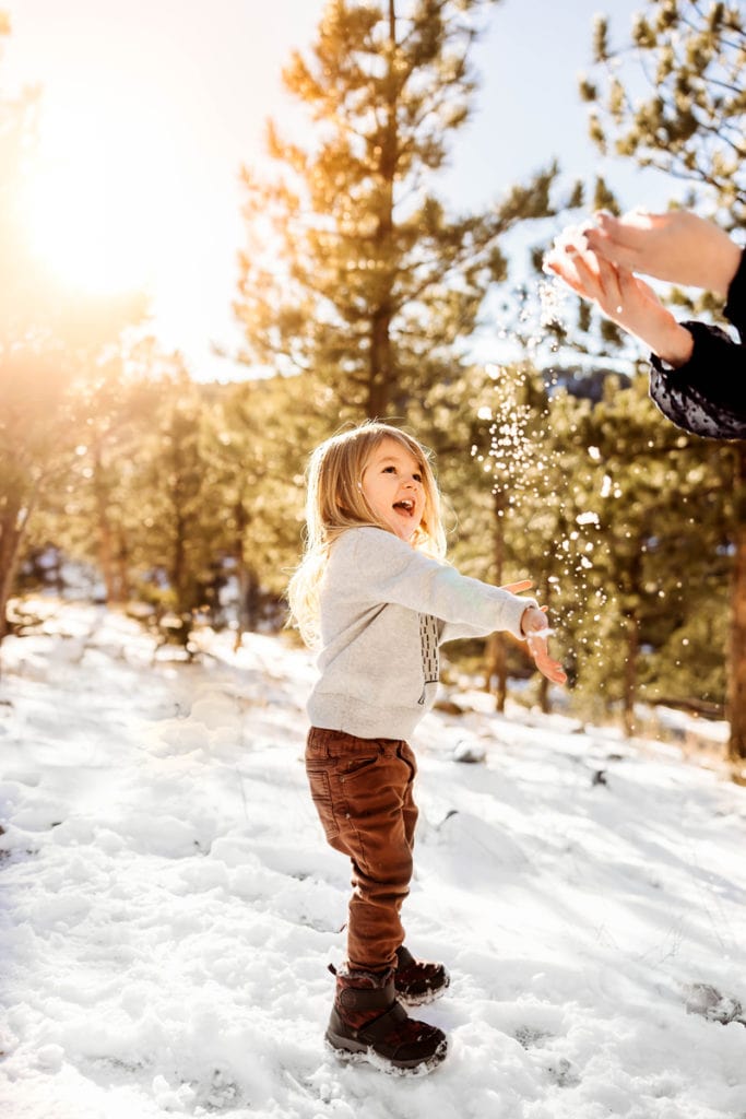 Family Photographer, a young child is happy standing in the snow