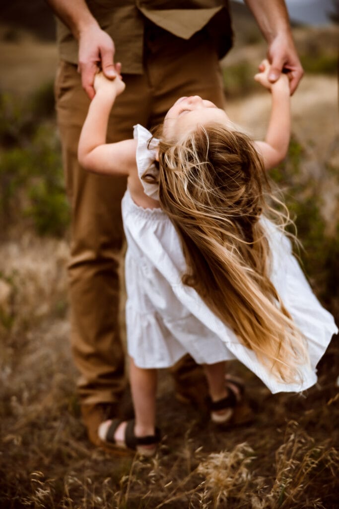 Family Photographer, a young girl dances with her father outside